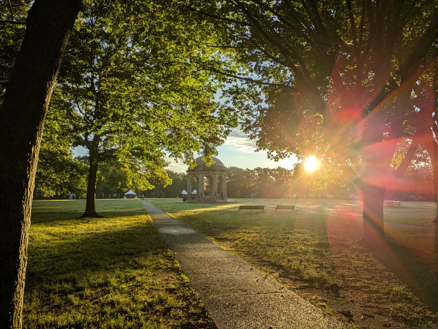 Golden morning sun shining through the trees behind the bandstand in Salem Common