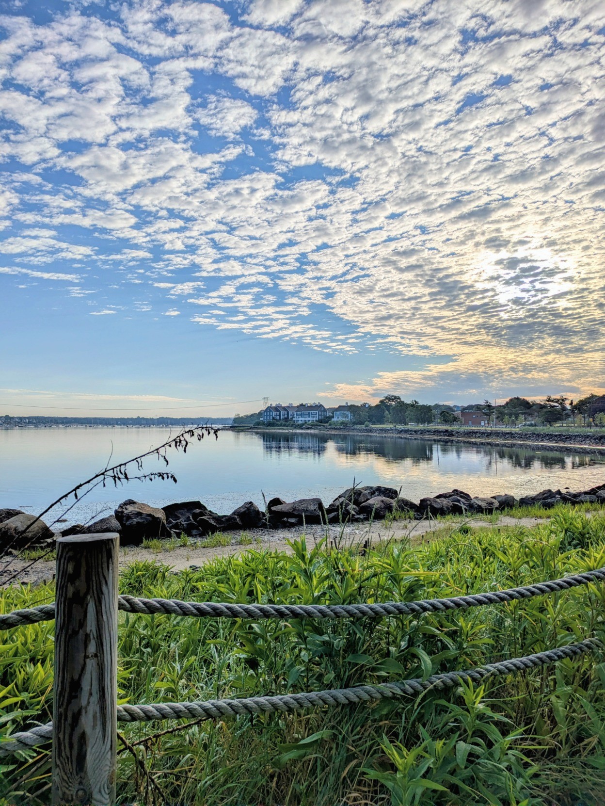 Harbor ocean view: the early morning sun is hiding behind the dappled sky, with fluffy clouds dotting the soft blue in a mackerel sky pattern